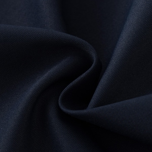 May include: Close-up of navy blue fabric with visible texture and folds. The fabric appears to be a tightly woven material, possibly for clothing or upholstery. The dark color and subtle sheen suggest a high-quality textile.