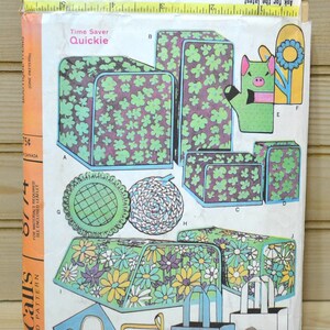 May include: A vintage McCall's sewing pattern for a quickie time saver. The pattern includes instructions for making a variety of items, including a bread basket, a toaster cover, a hot pad, and a tote bag. The pattern is printed on a white background with a colorful floral design.