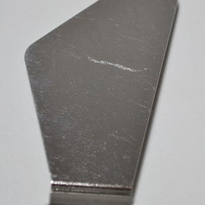 Pode incluir: Uma esp&aacute;tula offset de a&ccedil;o inoxid&aacute;vel com cabo preto. A esp&aacute;tula tem uma l&acirc;mina larga e angular, ideal para glac&ecirc; de bolos ou espalhar recheios. A l&acirc;mina tem aproximadamente 10 cm de comprimento.
