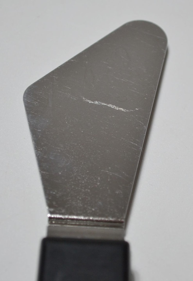 Pode incluir: Uma esp&aacute;tula offset de a&ccedil;o inoxid&aacute;vel com cabo preto. A esp&aacute;tula tem uma l&acirc;mina larga e angular, ideal para glac&ecirc; de bolos ou espalhar recheios. A l&acirc;mina tem aproximadamente 10 cm de comprimento.