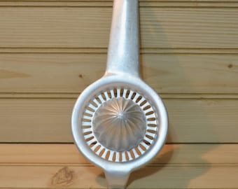 May include: A silver metal citrus juicer with a handle and a round, perforated base with a pointed center cone.
