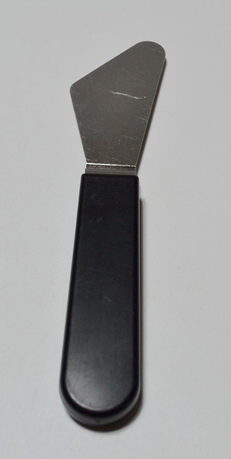 Pode incluir: Uma esp&aacute;tula de a&ccedil;o inoxid&aacute;vel com cabo preto. A esp&aacute;tula tem uma l&acirc;mina larga e plana e um cabo arredondado. A l&acirc;mina tem aproximadamente 7,6 cm de largura e 10,2 cm de comprimento. O cabo tem cerca de 10,2 cm de comprimento.