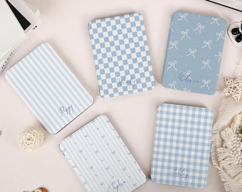 May include: Four rectangular e-reader cases in shades of light blue and white. One features blue stripes with the name Poppy, one a blue checkerboard with Wendy, one a blue bow pattern with Olivia, and one a blue gingham pattern with Ashley.