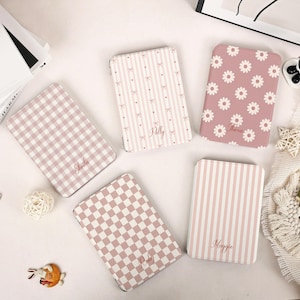 May include: Five rectangular cases in shades of pink and white. One features a pink and white gingham pattern with the name Sheila, one has pink stripes and bows with the name Polly, one has pink daisies with the name Thera, one has a pink checkerboard pattern with the name Ruby, and one has pink vertical stripes with the name Maggie.