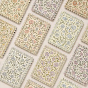 Puede incluir: Una colección de fundas rectangulares para tabletas con fondo crema y complejos patrones florales en tonos rosa, azul, amarillo y verde. Cada funda muestra un nombre único en letra cursiva, incluyendo Daphne, Hannah, Fanny, Alice, Belen, Kelly y Caroline.