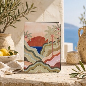 May include: A rectangular tablet case featuring a printed landscape illustration of rolling hills in shades of olive green, tan, and pink, with tall palm trees, a deep red sun, and a patch of blue water against a pale peach sky background.