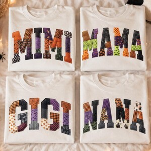 Könnte beinhalten: Vier weiße Rundhals-Sweatshirts mit großen, bogenförmigen Blockbuchstaben in einem bunten Patchwork-Muster zum Thema Halloween. Die Oberteile zeigen die Wörter MIMI, MAMA, GIGI und NANA, wobei jeder Buchstabe mit verschiedenen orangefarbenen, violetten, grünen und schwarzen Drucken gefüllt ist.