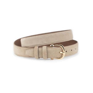 Op de afbeelding: Een beige suède riem met een goudkleurige gesp. De riem heeft een klassiek ontwerp met een enkele lus en een rechthoekige punt. De gesp heeft een eenvoudige, afgeronde vorm. De riem is waarschijnlijk gemaakt van echt suède leer.