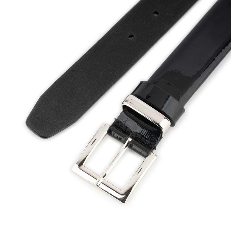 Black patent leather belt for men with silver buckle, slim glossy dress belt for formal wear and office outfits on white background