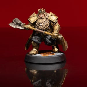 May include: A miniature figurine of a bearded dwarf king wearing gold-colored plate armor and a crown, holding a large battle axe. The figure features a black chainmail tunic, stands on a circular black base, and has detailed metallic textures.