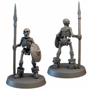 May include: Two grey miniature skeleton figures, one facing forward and the other backward. Each skeleton holds a spear and a shield. The figures are on grey circular bases, and wear boots. The skeletons are detailed and appear to be part of a fantasy game.
