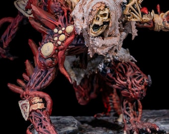 May include: A detailed, hand-painted miniature figure of a grotesque creature. The figure features a skull-like head, exposed bone, and fleshy, veiny limbs in shades of red and brown. The figure is posed on a rocky base, with a dark background.