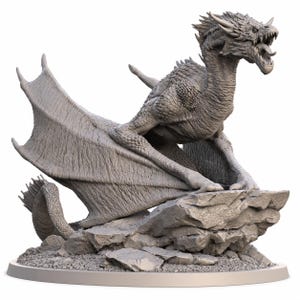 May include: A grey, unpainted dragon figurine perched on a rocky base. The dragon has detailed scales, large wings spread wide, and an open mouth showing teeth and a tongue. It is positioned on a circular platform, captured in a dynamic pose.