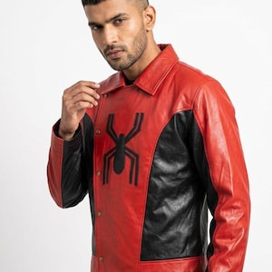 May include: Red and black leather jacket with a black spider emblem on the chest. The jacket has a collared neckline and button closure. The sleeves are long and the jacket appears to be made of genuine leather.