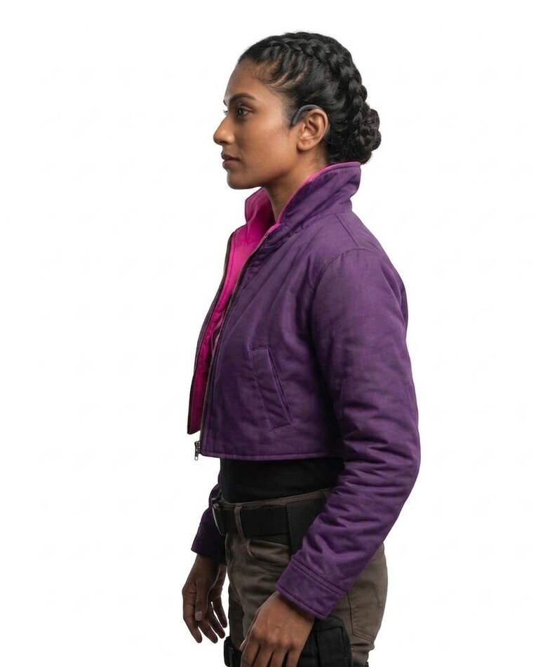 May include: A cropped jacket in a deep purple hue featuring a high collar and a vibrant hot pink interior lining. The jacket has long sleeves, a front zipper closure, and two side pockets, worn over a black top and dark brown utility trousers.