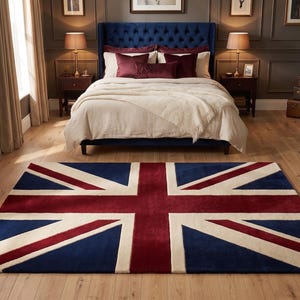 Può includere: Un tappeto rettangolare con il disegno della bandiera Union Jack nei colori rosso scuro, blu navy e crema. Il tappeto è posizionato su un pavimento in legno chiaro in una camera da letto. Un piccolo logo con il testo CHISHTI è visibile nell'angolo.