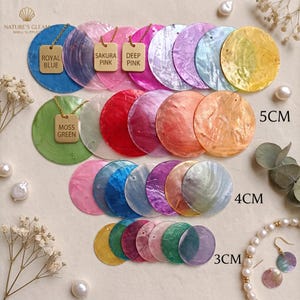 May include: A collection of circular shell discs in various colors and sizes, including 3cm, 4cm, and 5cm diameters. The discs feature iridescent surfaces and are arranged in rows. Some discs have gold-toned rectangular tags labeled Royal Blue, Sakura Pink, Deep Pink, and Moss Green attached by gold chains.