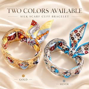 Puede incluir: Dos pulseras brazalete con pañuelo de seda, una en metal dorado y otra en metal plateado. Cada brazalete tiene una textura martillada y está entrelazado con un pañuelo de seda estampado atado en un lazo. Texto: TWO COLORS AVAILABLE SILK SCARF CUFF BRACELET.