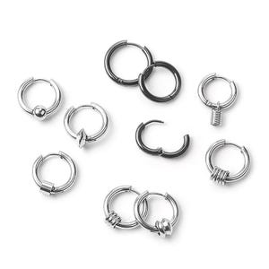 Può includere: Una collezione di orecchini a cerchio argentati in vari design. Alcuni cerchi hanno una sfera, una punta, un cilindro o una molla. Altri cerchi hanno più anelli o un design a nodo. Gli orecchini sono esposti su sfondo bianco.
