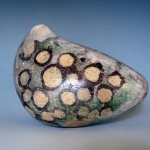 May include: A small, egg-shaped ceramic vase with a green, brown, and white speckled glaze. The vase has a unique, abstract design.