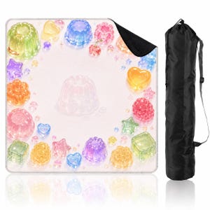 Puede incluir: Una alfombrilla cuadrada con fondo rosa claro decorada con un borde de formas coloridas y transl&uacute;cidas que parecen gelatina, incluyendo corazones, estrellas y postres moldeados, junto a una bolsa de transporte cil&iacute;ndrica negra con correa.