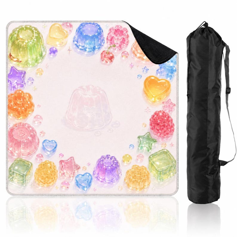 Puede incluir: Una alfombrilla cuadrada con fondo rosa claro decorada con un borde de formas coloridas y transl&uacute;cidas que parecen gelatina, incluyendo corazones, estrellas y postres moldeados, junto a una bolsa de transporte cil&iacute;ndrica negra con correa.