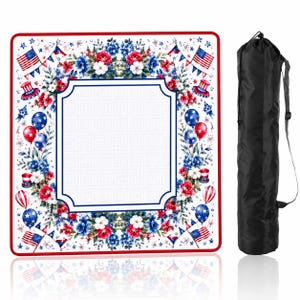 May include: A square outdoor blanket featuring a red, white, and blue floral pattern with American flags, balloons, and top hats surrounding a central white panel with a geometric border, accompanied by a black cylindrical carrying bag with a strap.