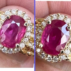 May include: A gold ring featuring a large oval ruby set within a halo of smaller diamonds.