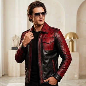 May include: A jacket featuring a combination of black leather and red snakeskin-patterned panels. The garment includes a collared neckline, a front zipper closure, long sleeves, and a single chest pocket with a flap. The design incorporates black leather on the torso and sleeves, contrasted with red snakeskin-textured sections on the shoulders, sleeves, and chest pocket.