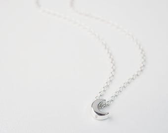 May include: A silver crescent moon pendant necklace on a delicate silver chain.