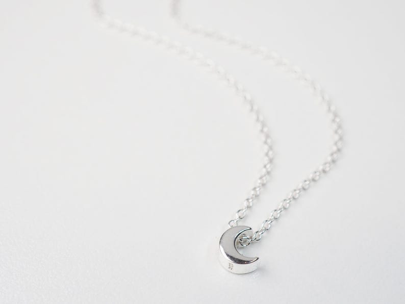 May include: A silver crescent moon pendant necklace on a delicate silver chain.