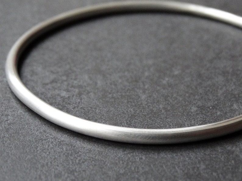 May include: A simple silver bangle bracelet with a smooth, polished finish.