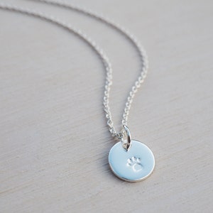 May include: A silver necklace with a small, round pendant featuring a paw print design.