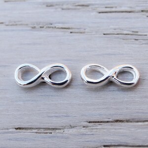 May include: Two silver infinity symbol charms, each with a smooth, polished finish. The charms are small and delicate, perfect for adding a touch of elegance to jewellery.