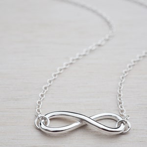May include: A silver infinity necklace with a delicate chain. The infinity symbol is a simple, elegant design.