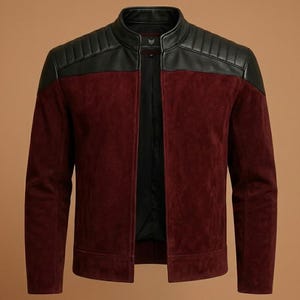 Puede incluir: Chaqueta de ante burdeos con cuello y detalles en los hombros de cuero negro. La chaqueta tiene cierre de cremallera frontal y un diseño clásico de chaqueta motera. Prenda de abrigo elegante.