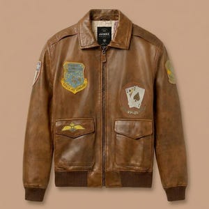 May include: Brown leather bomber jacket with a zip-up front, two front pockets, and a ribbed hem and cuffs. The jacket features embroidered patches on the chest and sleeves, including a patch with the text "STRATEGIC AIR COMMAND".