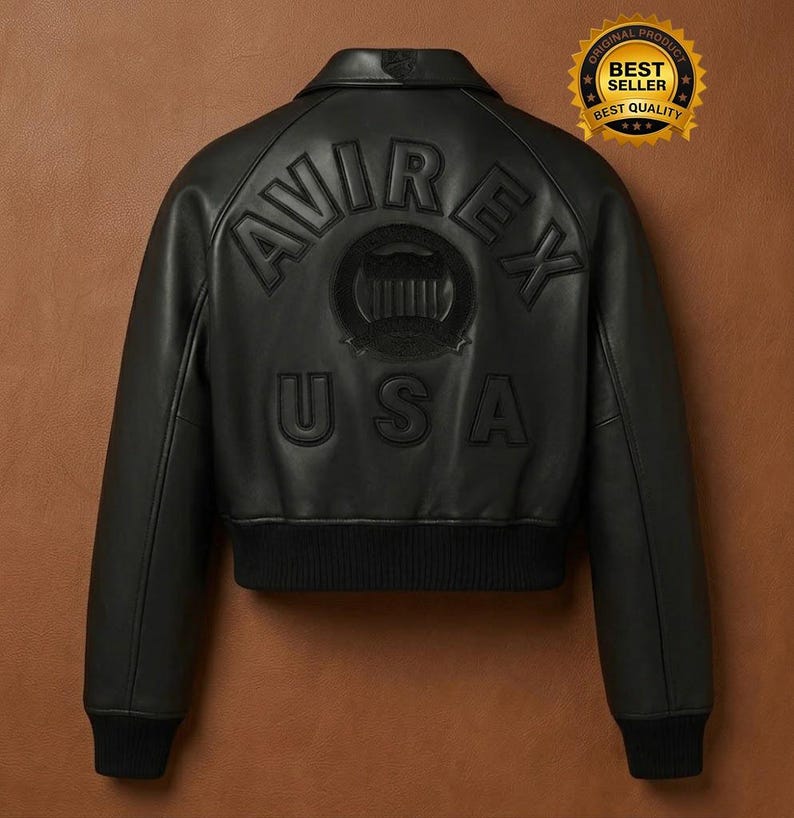 Op de afbeelding: Zwarte leren bomberjack met het woord "AVIREX" en "USA" in reli&euml;f op de rug. De jas heeft een geribbelde zoom en manchetten en een kleine kraag. Een gouden "Best Seller" sticker staat in de rechterbovenhoek.