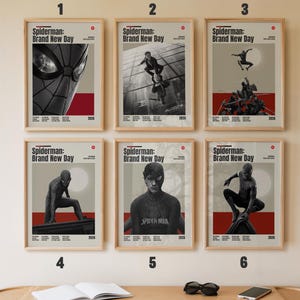 May include: Six framed posters titled Spiderman: Brand New Day, each featuring black and white imagery of the character in various poses, set against a light background with red accents, arranged in two rows of three on a plain wall.