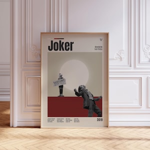 May include: A vertical movie poster for the film Joker, featuring the title in bold black text, a central graphic of a person holding a sign that reads EVERYTHING MUST GO, a figure dancing in a suit, and cast credits at the bottom in a light frame.
