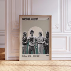 May include: A framed poster featuring the movie title "Dazed and Confused" with a group of men in vintage clothing. The poster has a retro design with a teal and beige color scheme, and the year 1993 is displayed.