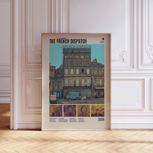 May include: Framed movie poster for "The French Dispatch" with a beige border. The poster features a European street scene with a blue van and a building. The title is at the top, with the film's name repeated. Below are actor headshots and the year 2020.