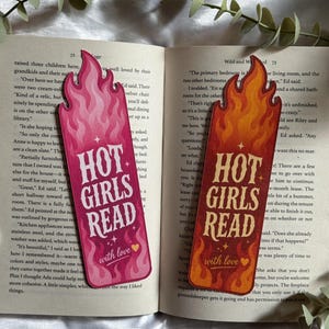 May include: Two flame-shaped bookmarks featuring the text "HOT GIRLS READ" and "with love" with a small heart icon. One bookmark is in shades of pink and magenta, while the other is in shades of orange and red, both with a stylized flame pattern.