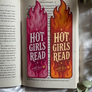 May include: Two rectangular bookmarks with flame-shaped tops. One is pink with white text, the other is orange and red with yellow text. Both feature the words "HOT GIRLS READ" and "with love" followed by a small heart symbol and star accents.