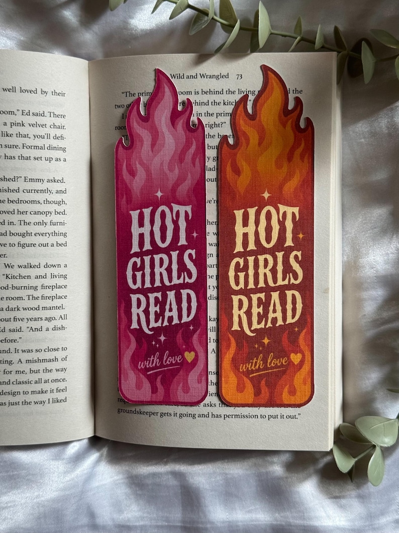 May include: Two rectangular bookmarks with flame-shaped tops. One is pink with white text, the other is orange and red with yellow text. Both feature the words "HOT GIRLS READ" and "with love" followed by a small heart symbol and star accents.