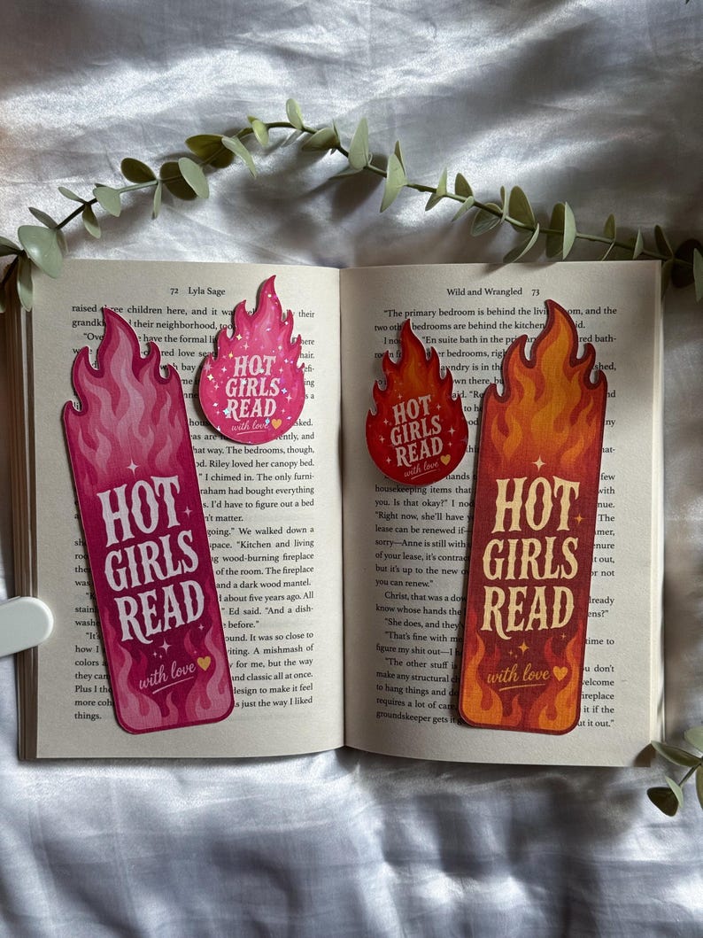 May include: Two tall bookmarks and two circular stickers featuring flame-shaped edges. The pink set and the orange-red set both display the text "HOT GIRLS READ" with "with love" and a small heart icon, placed on an open book page.