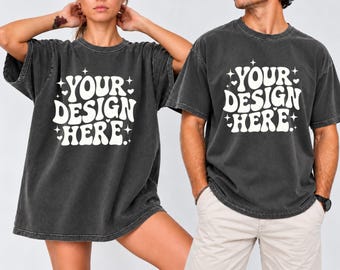 May include: Two charcoal gray short-sleeve t-shirts featuring a vintage-wash finish. Each shirt displays the white text "YOUR DESIGN HERE" in a bold, wavy font, surrounded by small white star and heart icons printed on the center of the chest.