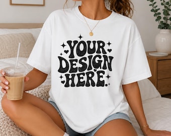 May include: A white short-sleeved t-shirt featuring the black text YOUR DESIGN HERE in a bold, wavy, retro-inspired font. The graphic is surrounded by small black star and heart icons, creating a playful and eye-catching design on the front.