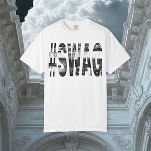 Könnte beinhalten: Weißes T-Shirt mit dem Wort "SWAG" in großen, schwarzen, stilisierten Buchstaben. Das Wort ist mit einem Schwarz-Weiß-Muster gefüllt. Das Hashtag-Symbol ist schwarz. Rundhalsausschnitt.