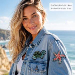 May include: A light blue denim jacket featuring two embroidered patches: a green and blue sea turtle patch measuring 6 x 4 cm and a red and blue starfish patch measuring 6 x 6 cm, both decorated with small beads and sequins.